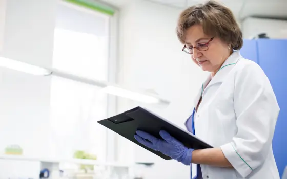 Female scientist reviewing information on a clipboard inside a pharmaceutical laboratory.