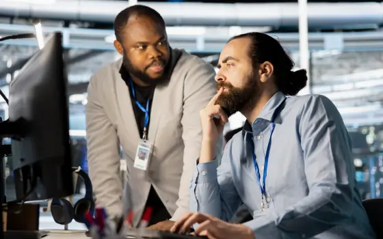 Two healthcare professionals discussing information while working at computer stations.