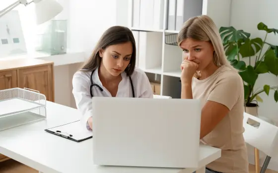 Two female doctors examining patient data together in a clinical setting.