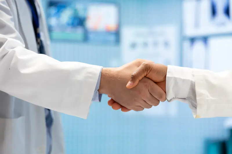Two pharmaceutical researchers in lab coats reviewing a research document beside lab glassware.