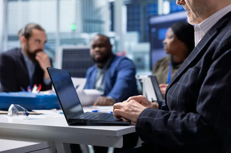 Scientist in a lab coat pointing at a computer screen while consulting with a male executive in a high-tech office.