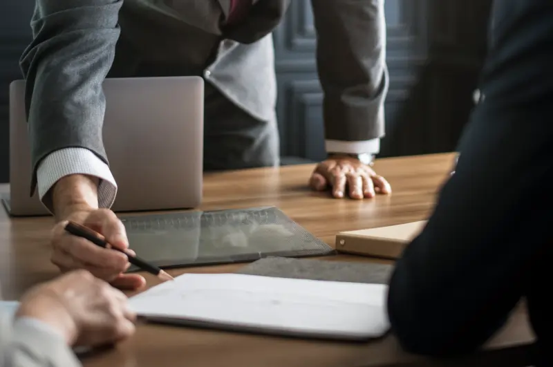 Workers monitoring yellow pills on a conveyor belt in a pharmaceutical manufacturing cleanroom.