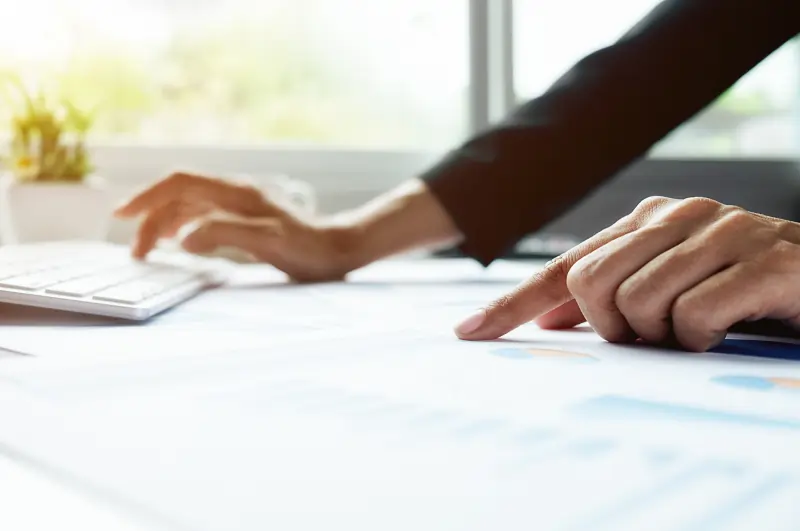 Female laboratory scientist in safety goggles and a lab coat working at a computer in a laboratory.