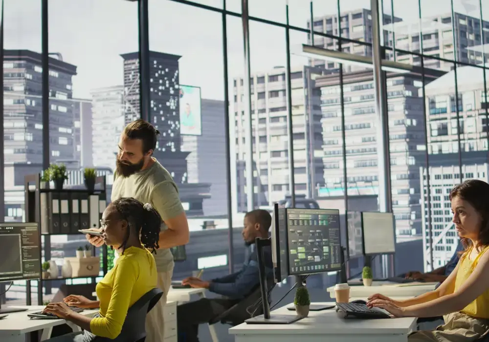 Professionals working together in a tech driven office environment with multiple digital workstations.
